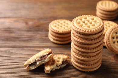 Tasty sandwich cookies with cream on wooden table, closeup. Space for text