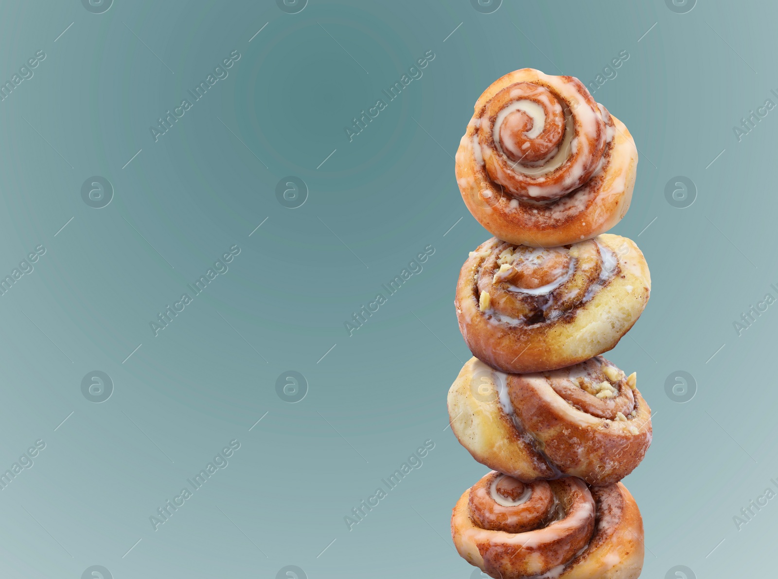 Image of Cinnamon rolls balancing on light blue background, space for text