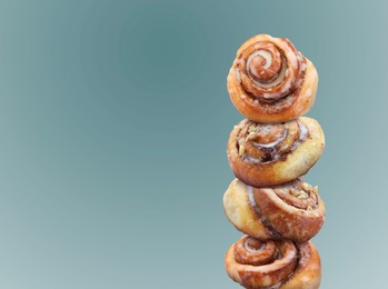 Image of Cinnamon rolls balancing on light blue background, space for text