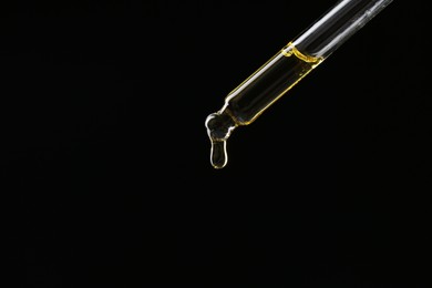 Photo of Dripping tincture from pipette on black background, closeup. Space for text