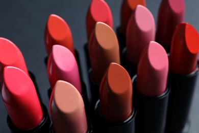 Photo of Set of different lipsticks on grey background, closeup. Cosmetic product