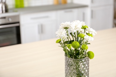 Photo of Vase with beautiful flowers on table in kitchen interior. Space for text