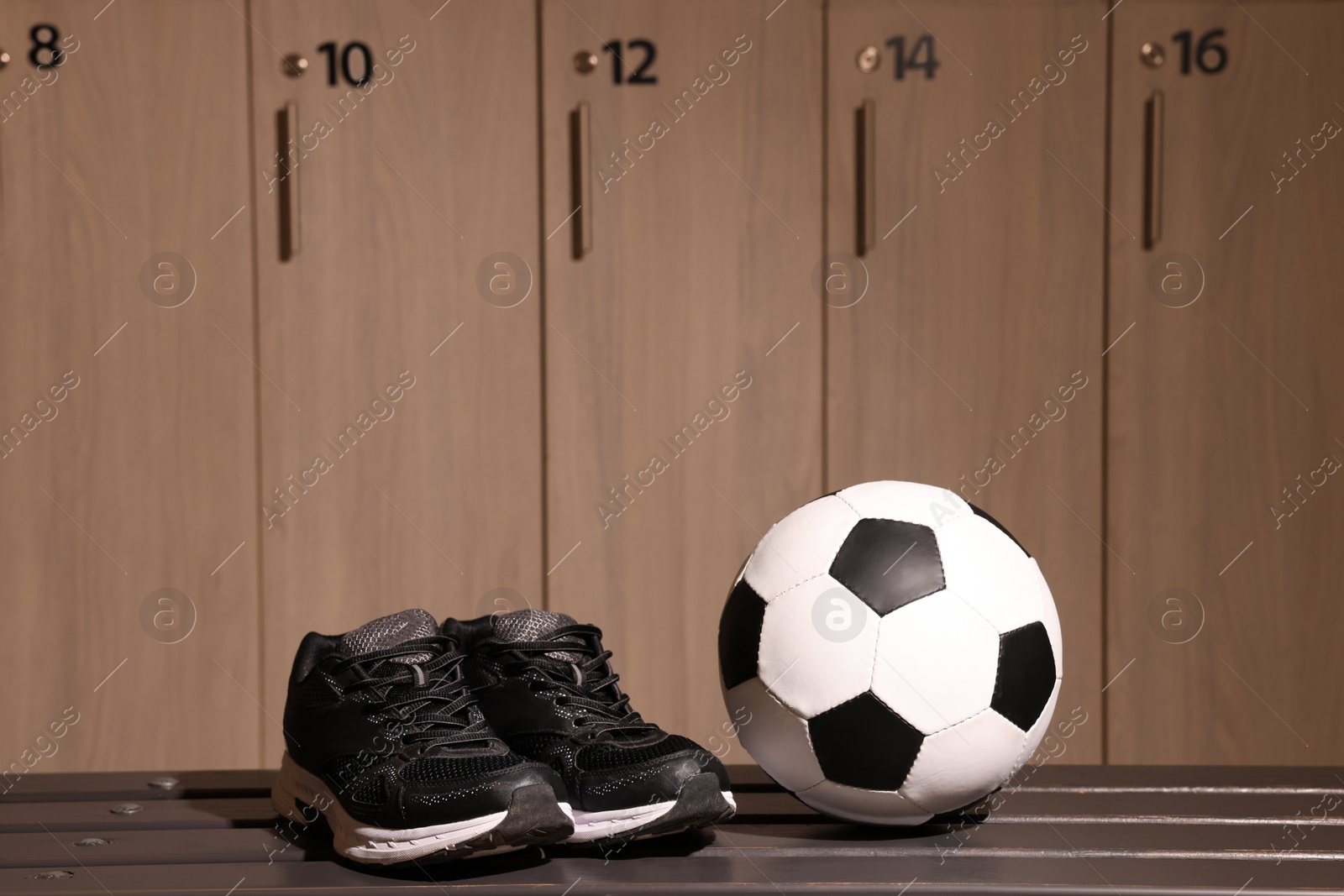 Photo of Soccer ball and sneakers on wooden bench in locker room