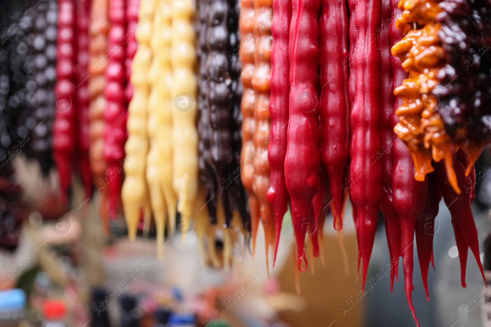 Photo of Bunches of different delicious churchkhelas at market, closeup. Space for text