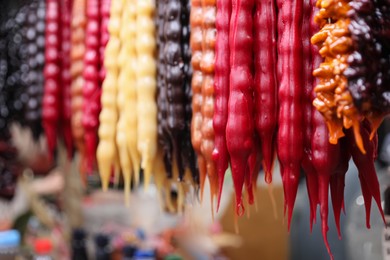 Photo of Bunches of different delicious churchkhelas at market, closeup. Space for text