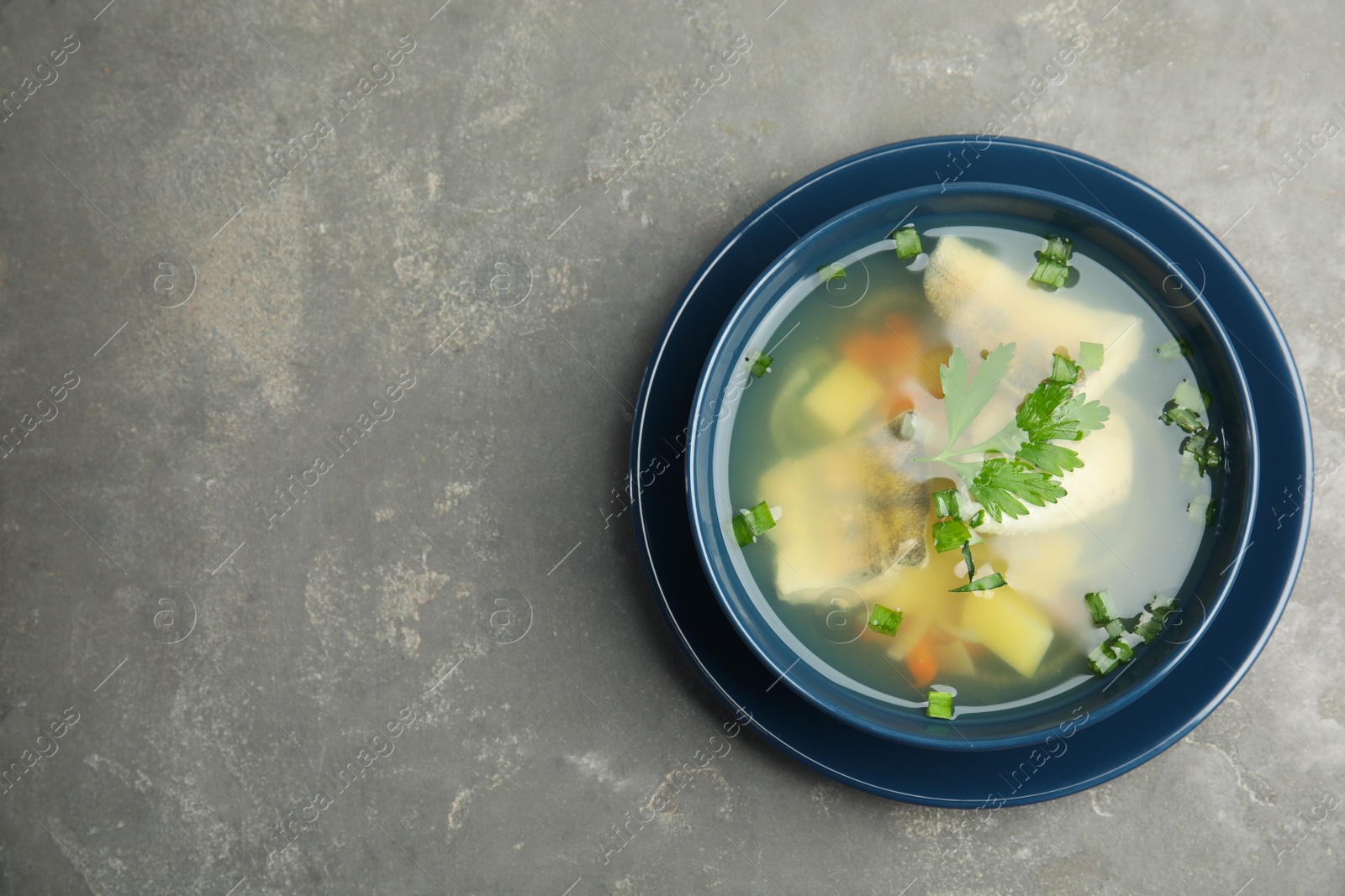 Photo of Delicious fish soup in bowl on grey table, top view. Space for text