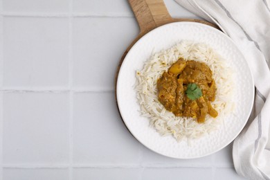 Photo of Delicious chicken curry with rice on white tiled table, top view. Space for text