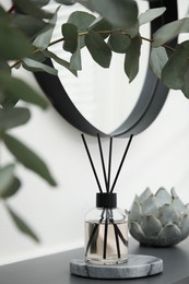 Photo of Reed diffuser and home decor on grey table near white wall