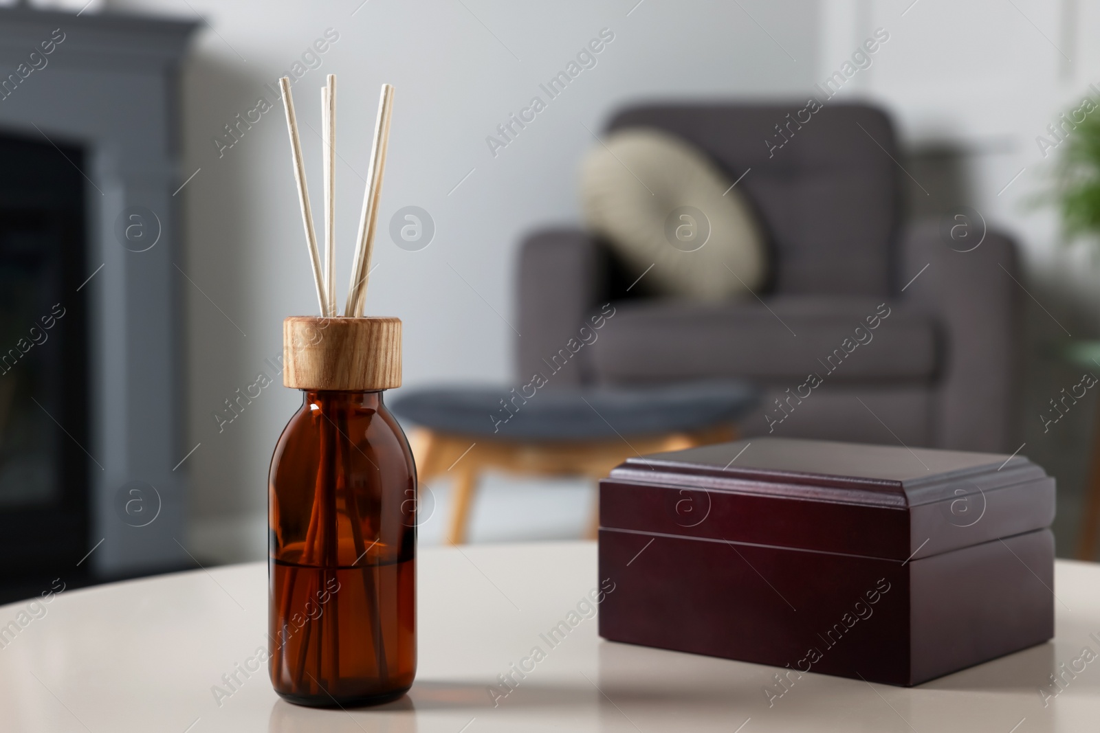 Photo of Aromatic reed air freshener and wooden box on light table indoors