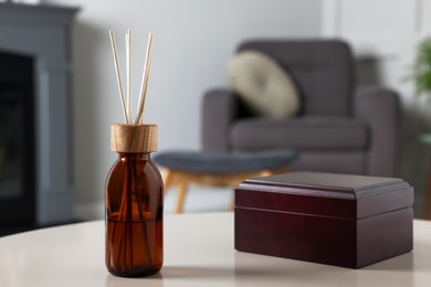 Aromatic reed air freshener and wooden box on light table indoors