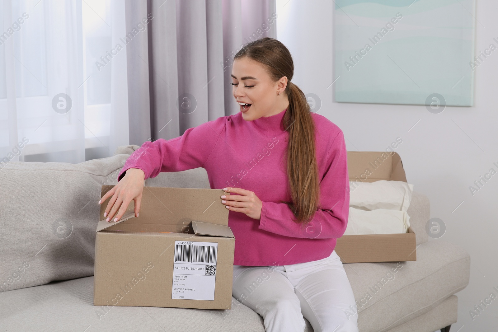 Photo of Emotional woman unpacking parcel at home. Online store