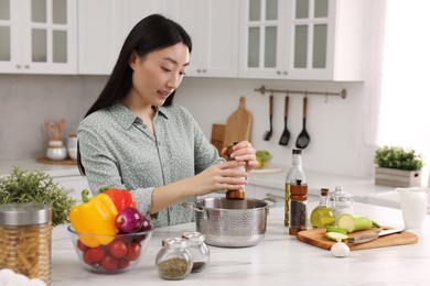 Beautiful woman cooking at countertop in kitchen