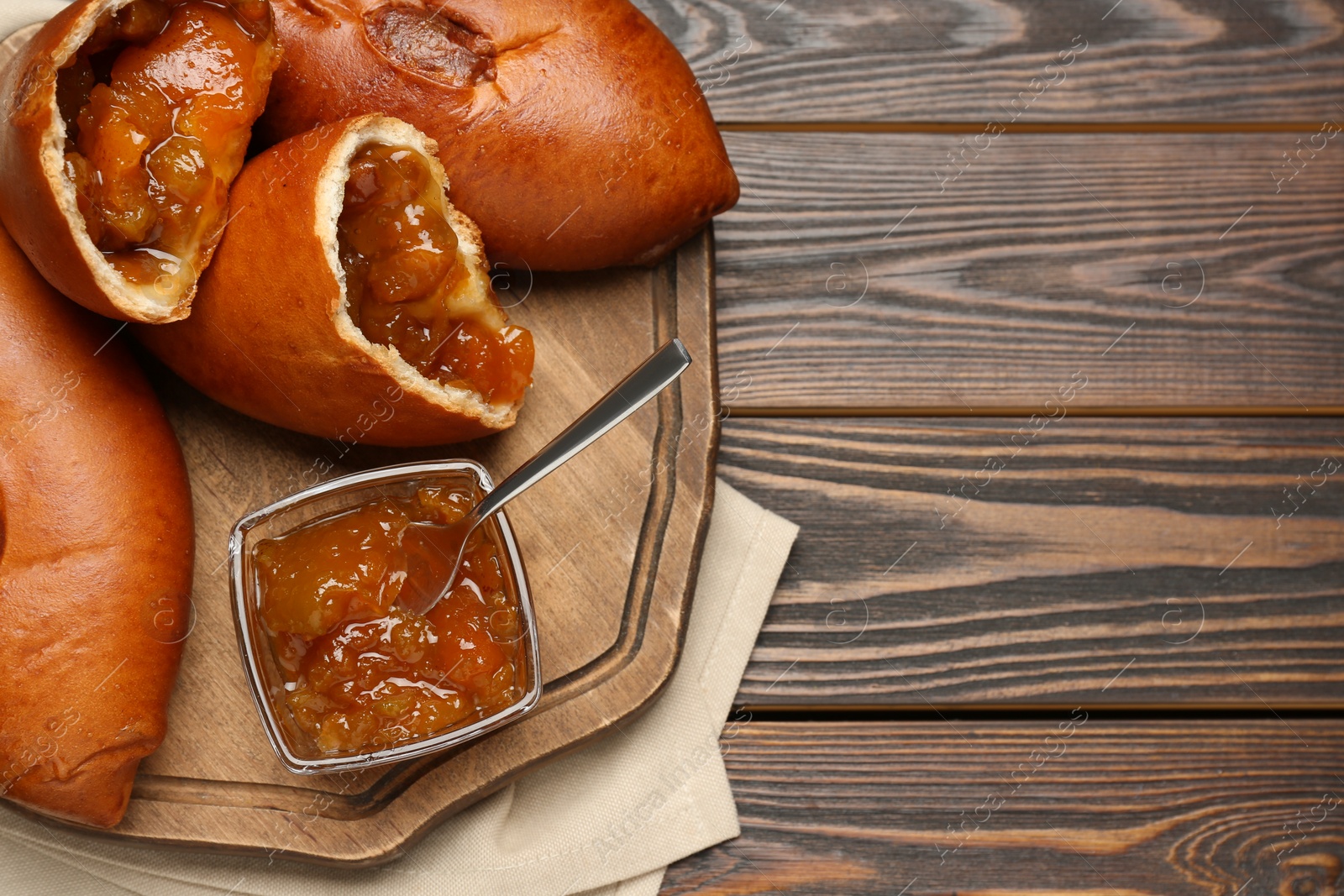 Photo of Delicious baked patties with jam on wooden table, top view. Space for text