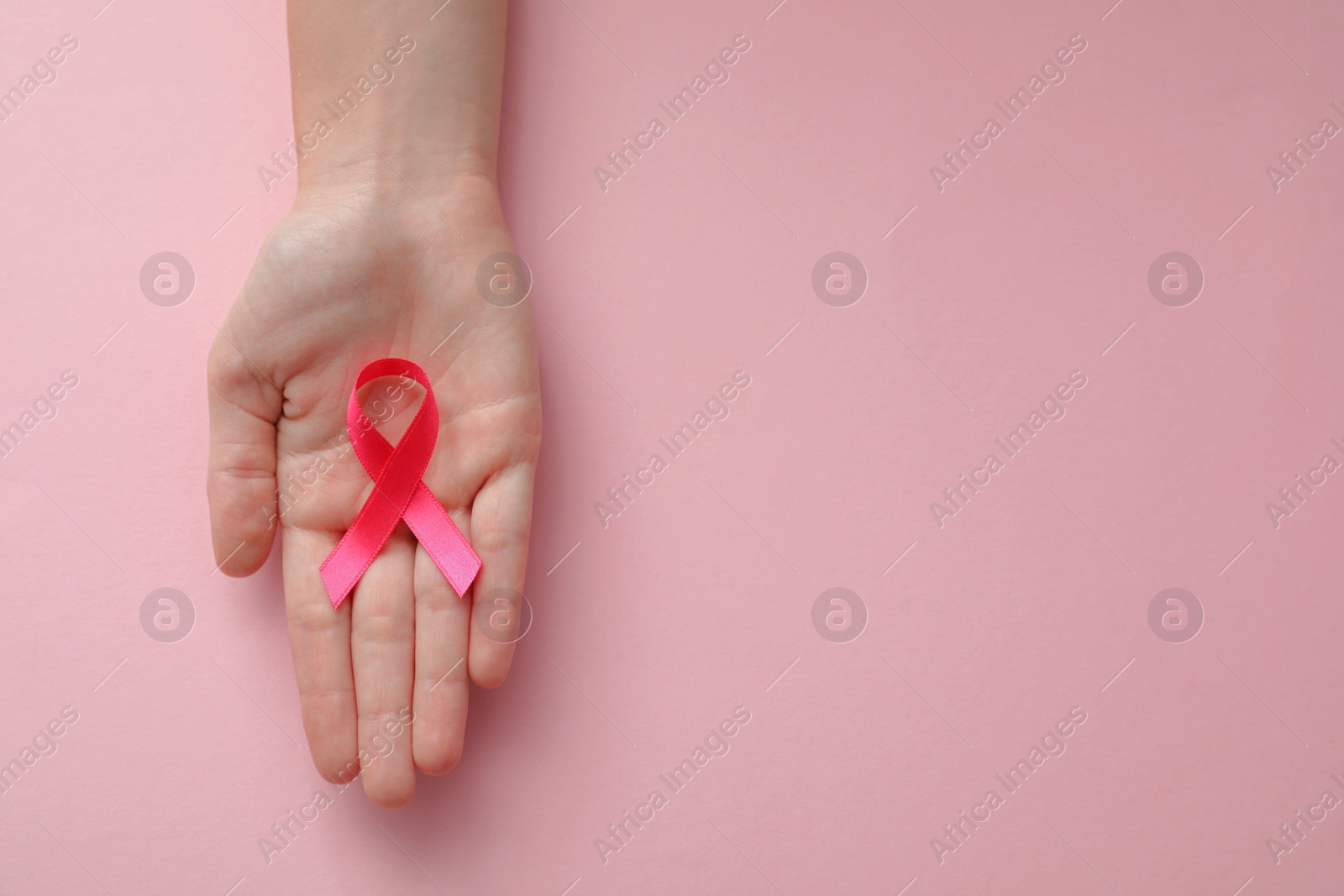 Photo of Woman holding pink ribbon on color background, top view with space for text. Breast cancer awareness concept