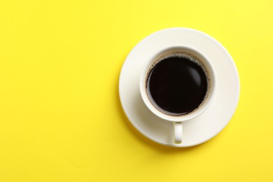 Photo of Cup of aromatic coffee on yellow background, top view. Space for text