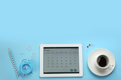 Modern tablet with calendar app on light blue background, flat lay. Space for text