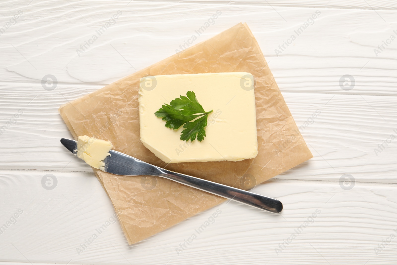 Photo of Tasty butter and knife on white wooden table, top view