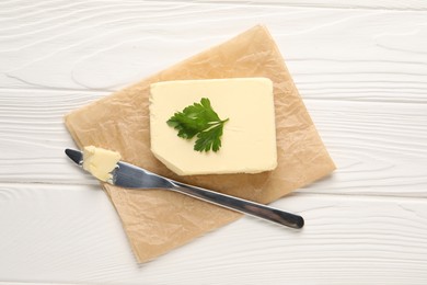 Tasty butter and knife on white wooden table, top view