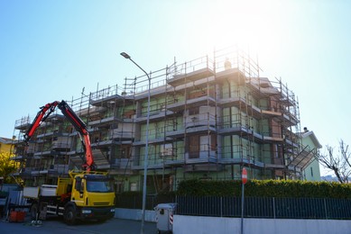 Scaffolding near modern building and truck crane on road