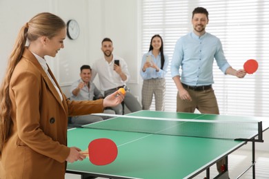 Photo of Business people playing ping pong in office