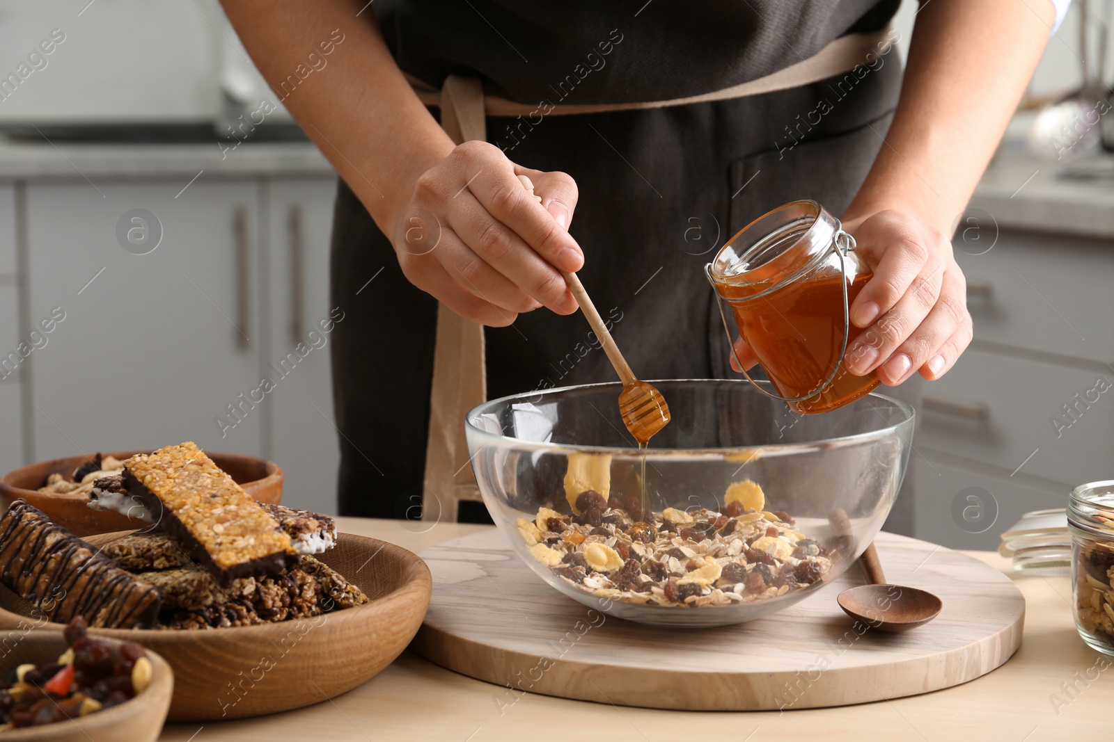 Photo of Woman preparing healthy granola bar at wooden table in kitchen