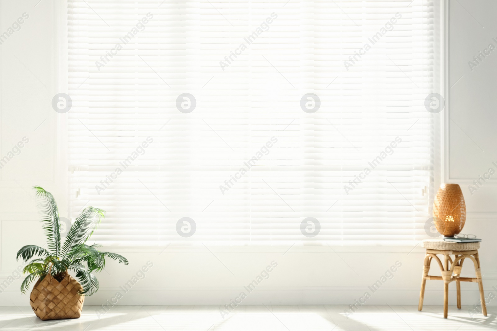 Photo of Stool, lamp and plant near big window in spacious room. Interior design
