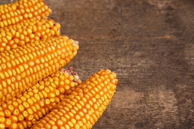 Photo of Delicious ripe corn cobs on wooden table, closeup. Space for text