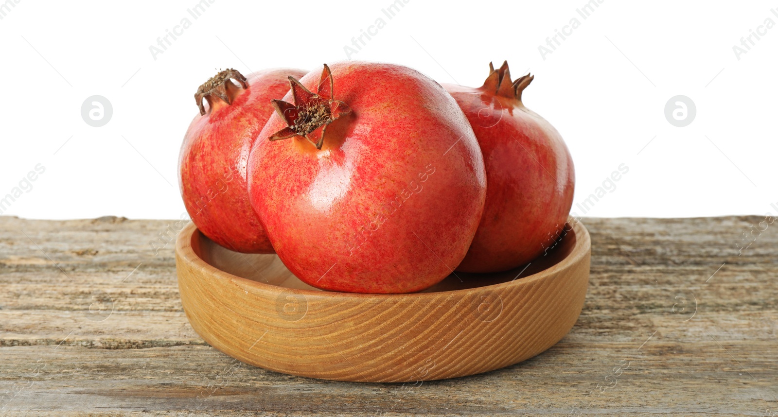 Photo of Fresh pomegranates in bowl on wooden table against white background