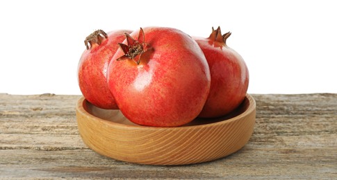 Fresh pomegranates in bowl on wooden table against white background