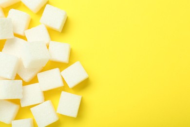 White sugar cubes on yellow background, top view. Space for text