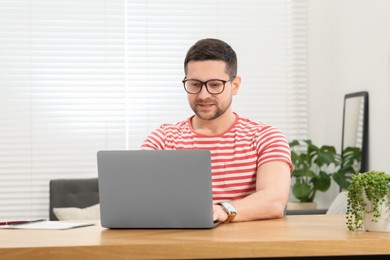 Photo of Man working with laptop at wooden table at home