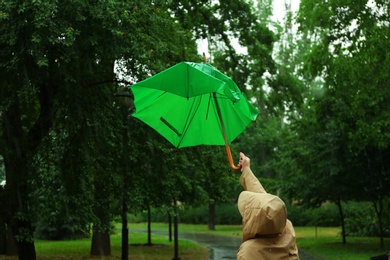Photo of Woman with broken green umbrella in park on rainy day