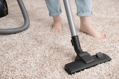 Woman cleaning carpet with vacuum cleaner, closeup. Space for text