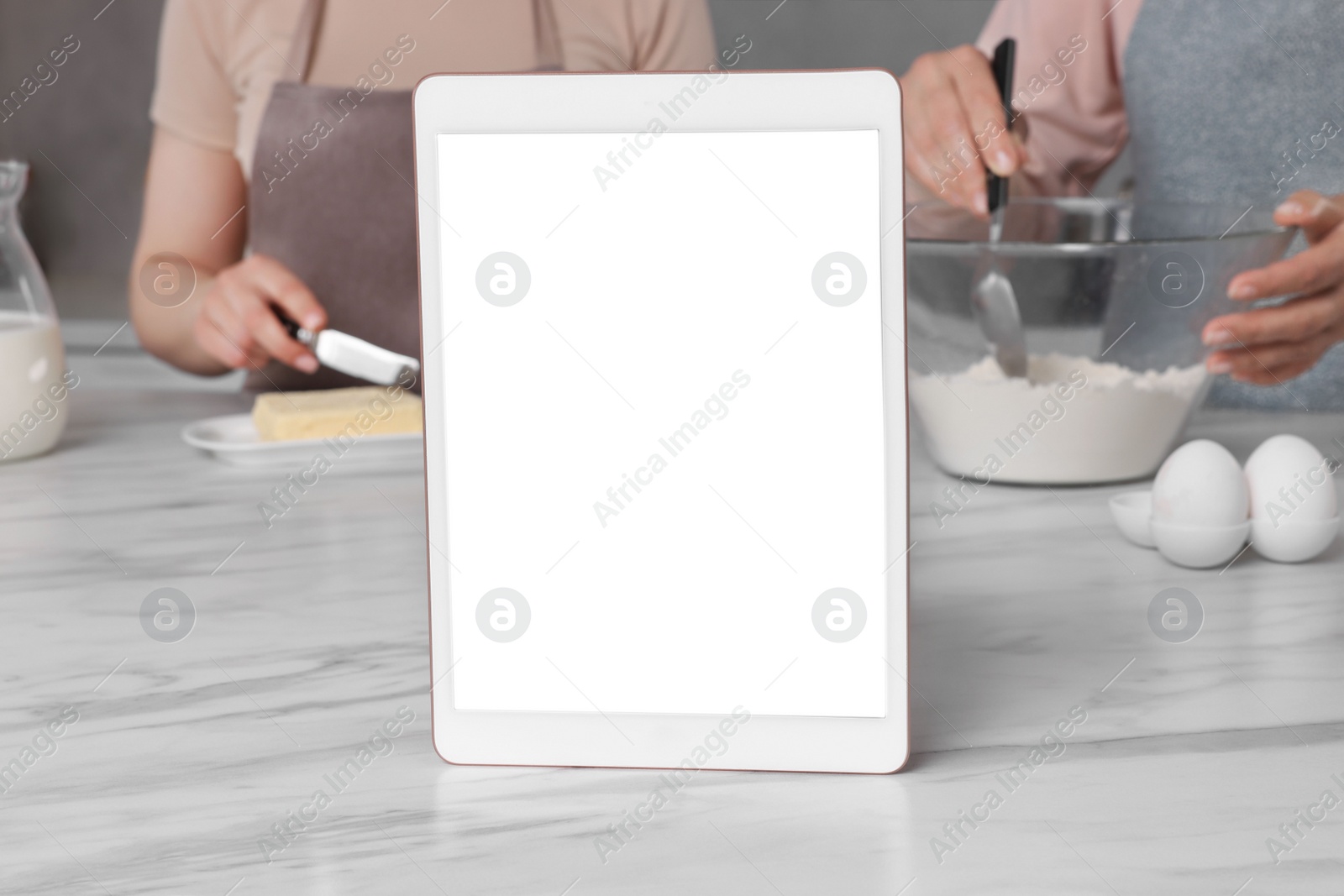 Photo of Modern tablet with blank screen on white marble table in kitchen