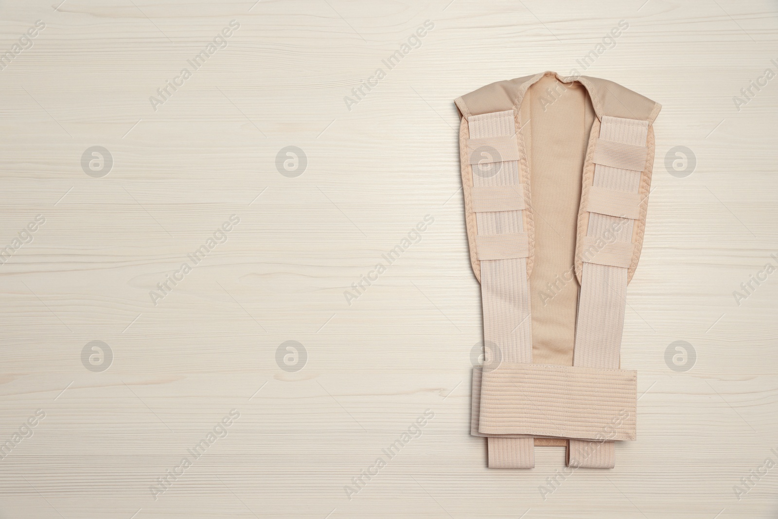 Photo of Beige posture corrector on white wooden table, top view. Space for text