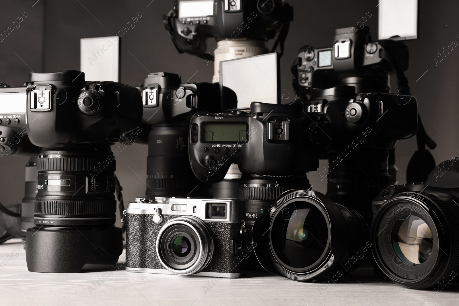 Photo of Modern cameras on white wooden table, closeup