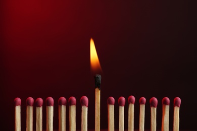Photo of Burning match among others on color background. Difference and uniqueness concept