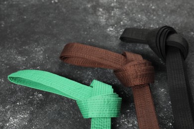 Photo of Colorful karate belts on gray background, flat lay