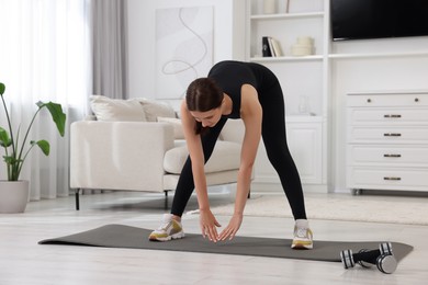 Photo of Morning routine. Sporty woman doing stretching exercise at home