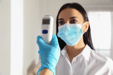 Photo of Doctor measuring woman's temperature in office, closeup. Prevent spreading of Covid-19