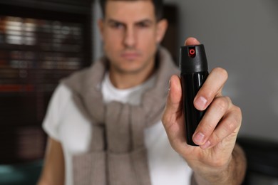 Photo of Man using pepper spray indoors, focus on hand
