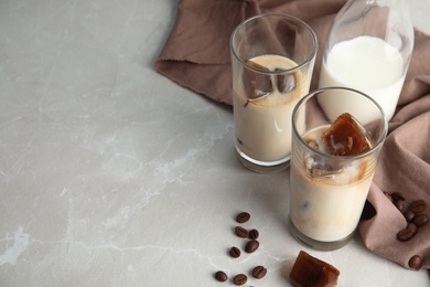 Glasses of milk with coffee ice cubes on grey table. Space for text