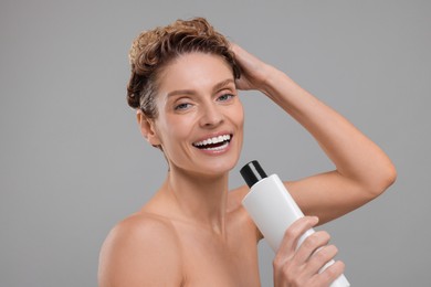Photo of Portrait of happy woman with bottle singing while washing hair on light grey background