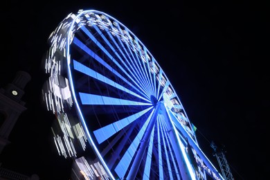 Beautiful glowing Ferris wheel against dark sky, low angle view