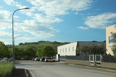 Parking lot with cars near factory building in countryside on sunny day