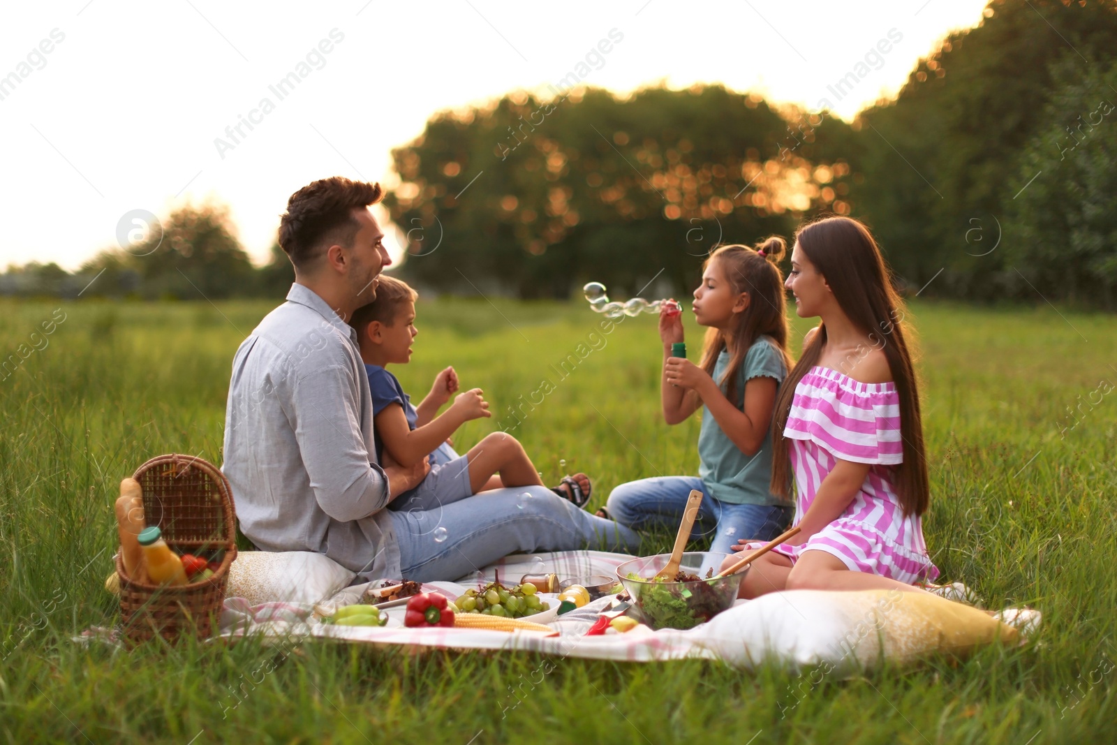 Photo of Happy family having picnic in park at sunset