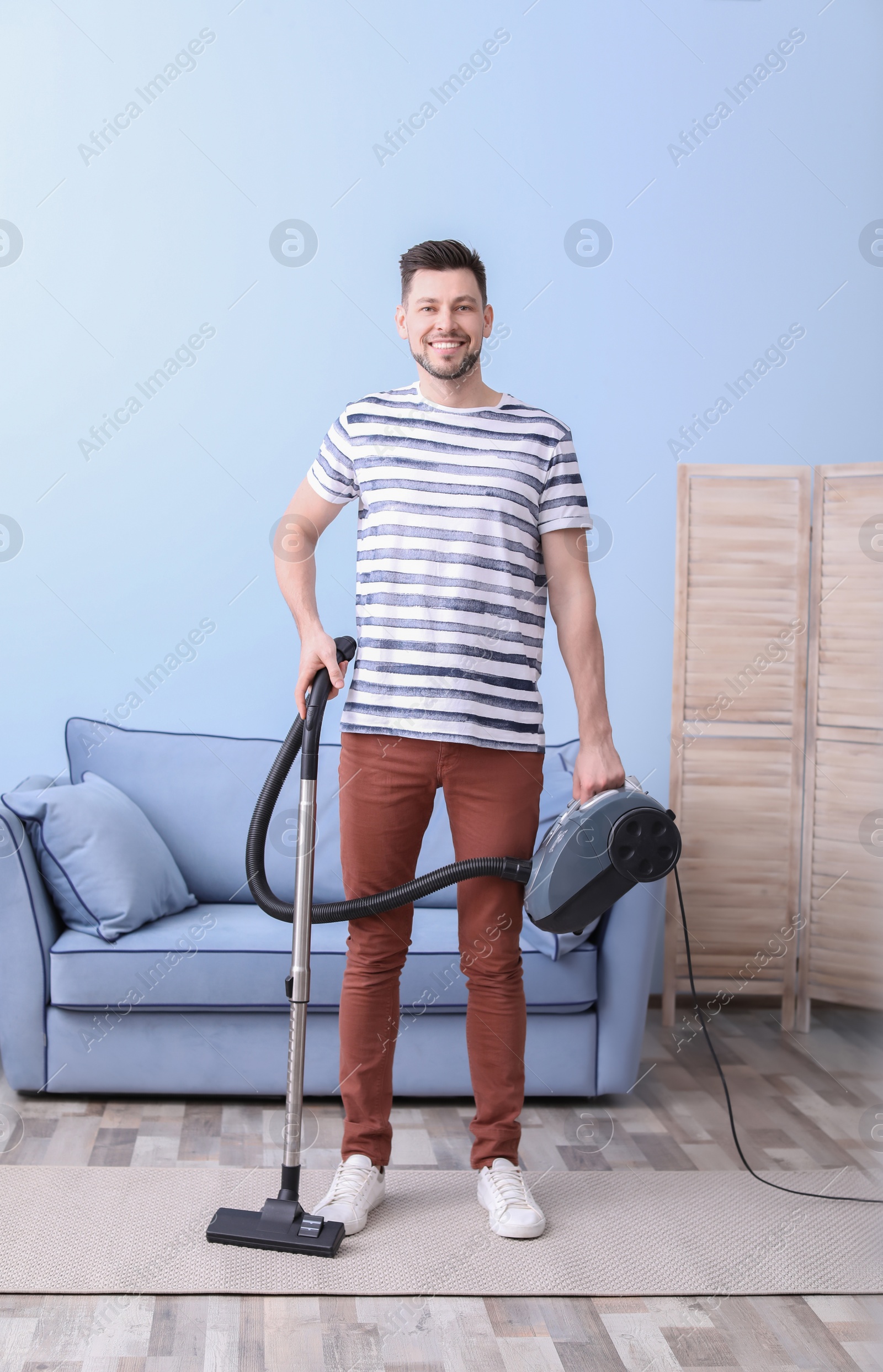 Photo of Mature man hoovering carpet with vacuum cleaner in living room