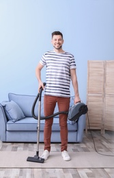 Mature man hoovering carpet with vacuum cleaner in living room