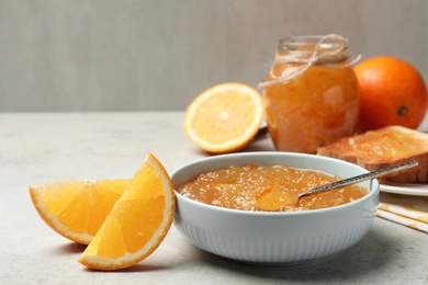 Photo of Delicious orange marmalade in bowl on light grey table. Space for text