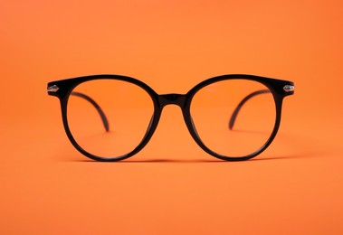 Glasses in stylish frame on orange background